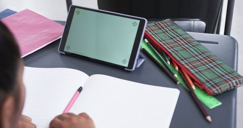Student Writing in Classroom with Tablet on Desk for Education Concept