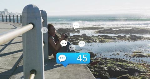 Sitting on seawall photographing rocky coastline while receiving 45 chat notifications