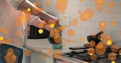 Pouring fresh coffee grounds from grinder into brewer on modern kitchen countertop