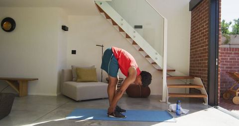 African American Man Stretching at Home in Modern Living Room