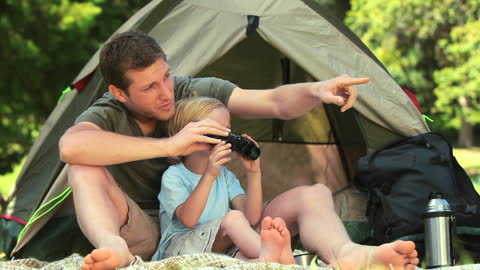 Father and Son Birdwatching Outside Tent in Park with Binoculars
