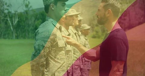 Drill instructor pointing at soldier during outdoor formation training with camouflage uniforms