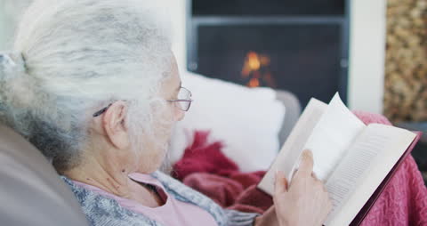 Senior Woman Relaxing by Fireplace with Book