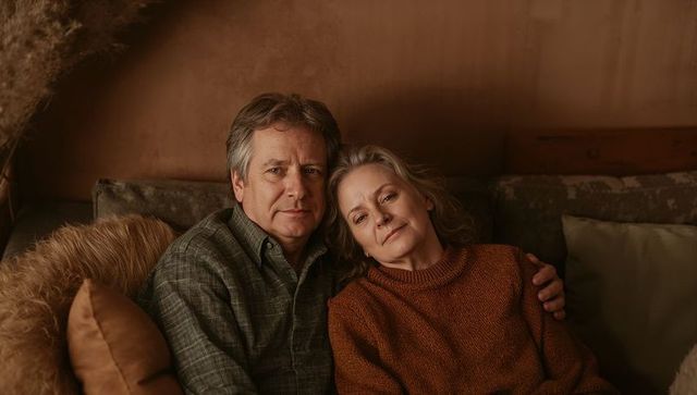 Mature couple relaxing on sofa in cozy neutral living room, intimate autumn portrait