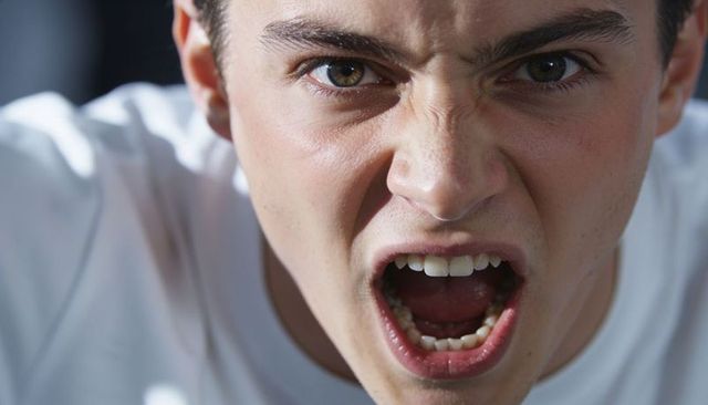 Angry teen shouting closeup portrait showing open mouth and tense expression