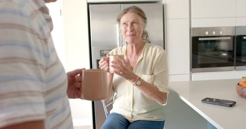 Mature Couple Sharing Morning Coffee in Kitchen with Warm Smiles