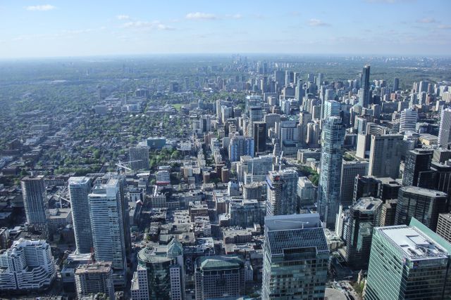 Panoramic view of a cityscape from a high vantage point, showcasing numerous skyscrapers and diverse architectural styles against a vast horizon. Ideal for use in urban development presentations, real estate advertisements, or travel promotions highlighting city life and vibrant business districts.