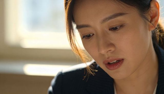 Thoughtful professional woman gazing down with soft backlight by office window portrait