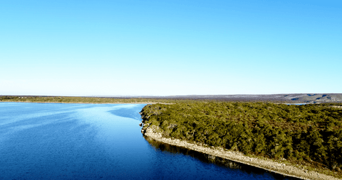 transparent water embracing grassy hill beneath clear sky serenity - Download Free Stock Videos Pikwizard.com