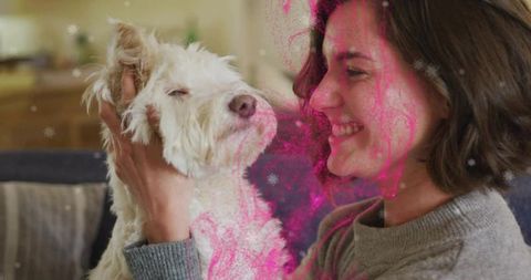 Smiling woman cradling scruffy white dog on couch with pink sparkle overlay cozy moment