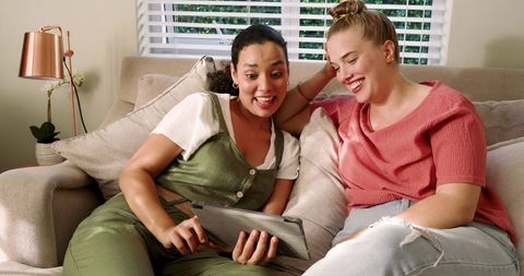 Female friends relax emotionally interactive with tablet at home