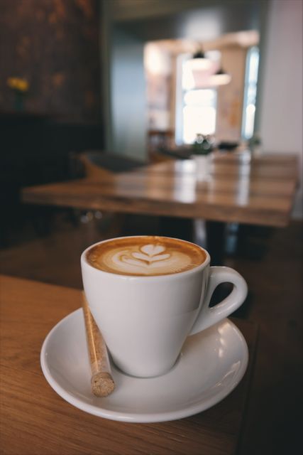 A warming latte with intricate latte art in a cozy cafe. Perfect for use in food and drink advertisements, coffeehouse promotions, blogs about cafe culture or caffeine, and social media posts highlighting a relaxing morning scene.