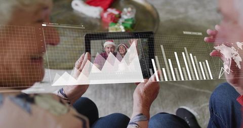 Senior couple holding tablet during virtual holiday call with ar data overlays and charts