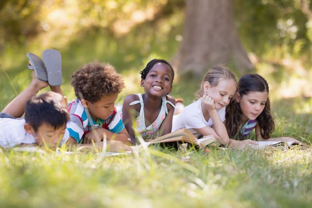 Group of children lying on grass, reading books together on a sunny day. Perfect for educational content, summer camp promotions, outdoor activities, and childhood bonding themes.
