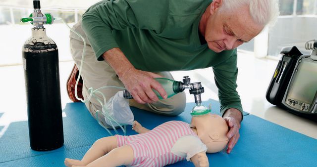 A senior Caucasian man is practicing infant CPR on a mannequin, demonstrating the setup of oxygen delivery equipment, with copy space. His focus and care in the training scenario underscore the importance of emergency response skills.