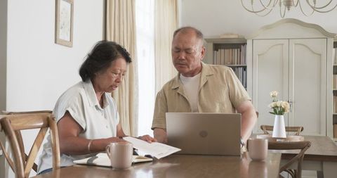 Senior couple discussing finances at home with laptop and documents