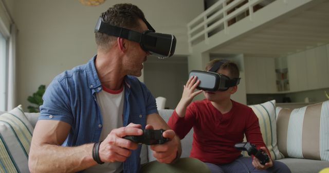 Father and son enjoying using virtual reality goggles together in the comfort of a modern living room. Ideal for content depicting family bonding, gaming experiences, or the use of modern technology in home settings. This image captures a joyful and interactive moment that can be used in promotional materials for VR products, tech gadgets, family-oriented content, or lifestyle blogs.