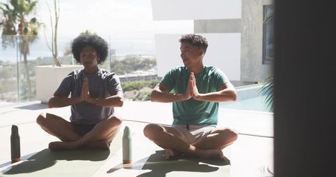 Sunlit outdoor yoga for men practicing meditation and mindfulness on modern terrace