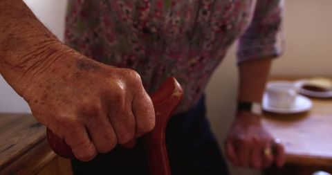 Senior woman with wooden cane in kitchen environment