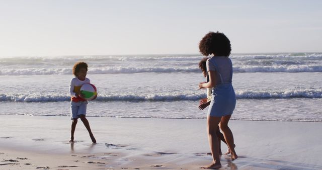 African american mother and her children playing with a ball on the beach. healthy outdoor leisure time by the sea.