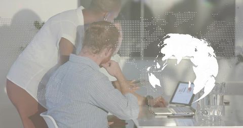 Collaborating team analyzing global data on laptop with dotted world map and glass table