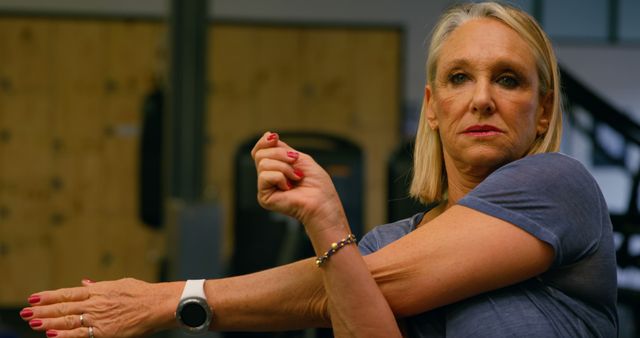 Senior Woman Stretching Arm in Gym Wearing Fitness Watch - Download Free Stock Images Pikwizard.com