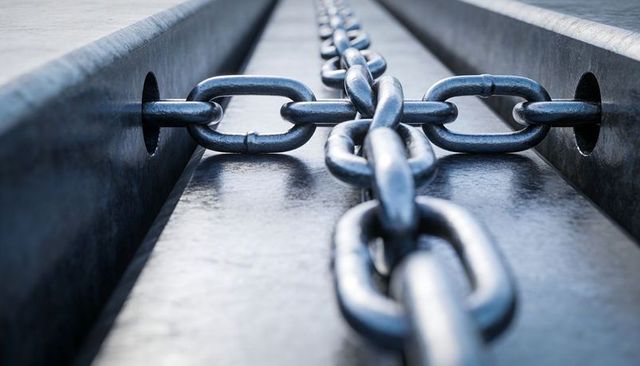 Heavy steel chain running through recessed dock trough close-up industrial texture and depth