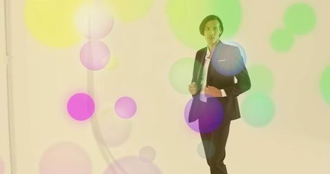 Fashion model adjusting suit jacket in colorful studio