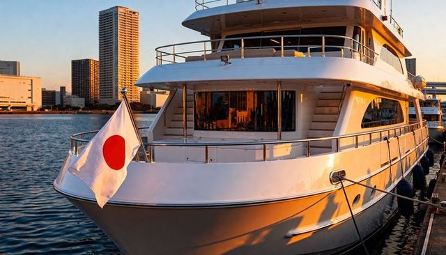 Luxury white superyacht flying japanese flag mooring at city marina during golden sunset