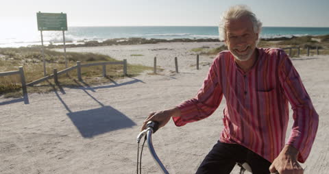 Senior Man Smiling with Bicycle on Sunny Beach Path