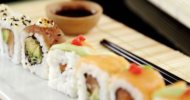 A variety of sushi rolls are elegantly presented on a plate, accompanied by soy sauce for dipping. Sushi, a traditional Japanese dish, is enjoyed worldwide for its fresh flavors and artistic presentation.