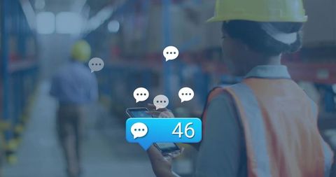 Warehouse worker checking smartphone with 46 message notifications, wearing hard hat and safety vest