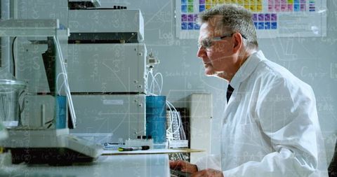 Senior scientist operating HPLC and monitoring chromatogram data on screen in laboratory