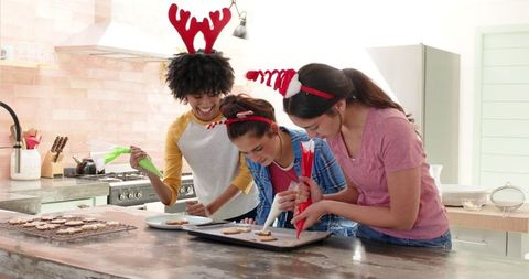 Diverse Friends Decorating Holiday Cookies with Joyful Antlers