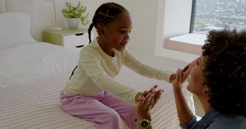 Mother and daughter playing in bright bedroom setting