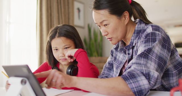 Image of happy asian mother and daughter doing homework together. Family, motherhood, relations and spending quality time together concept digitally generated image.