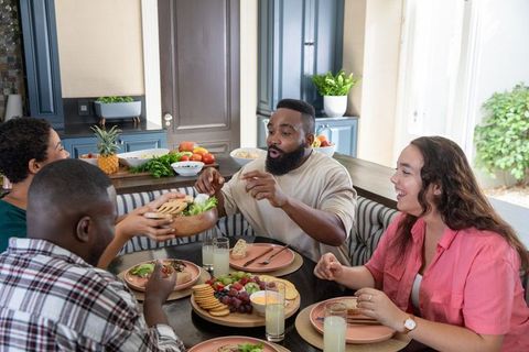 Diverse Friends Enjoying Meal and Sharing Salad in Cozy Kitchen