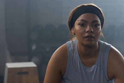 African american woman catching breath after intense training session in gritty gym studio