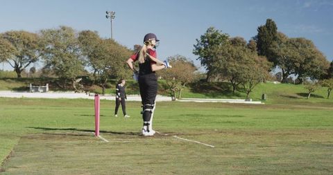 Female cricket player poised in batting stance on sunny day
