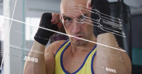 Muscular boxer raising guarded fists training with heavy bag and futuristic hud overlay