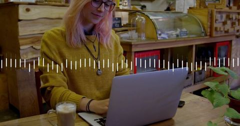 Freelancer working on laptop in cozy cafe with latte and audio waveform overlay