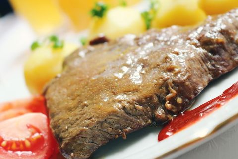 Juicy beef steak glazed with brown gravy served with boiled potatoes and sliced tomatoes