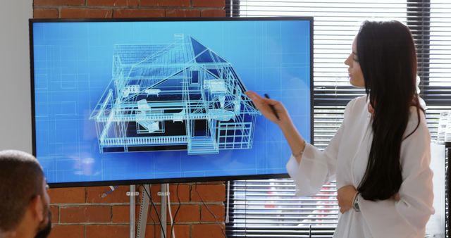 Architect presenting a digital house model on a large screen during a meeting with team members. Use this for topics related to architecture, architectural presentations, design technology, collaborative work in architecture, and construction planning.