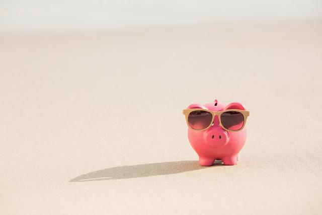 Pink piggy bank wearing sunglasses on sandy beach. Perfect for illustrating concepts of summer savings, vacation funds, financial planning for holidays, and fun money management. Ideal for use in travel blogs, financial advice articles, and summer-themed promotions.