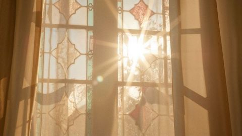 Sunburst through stained glass window with beige curtains