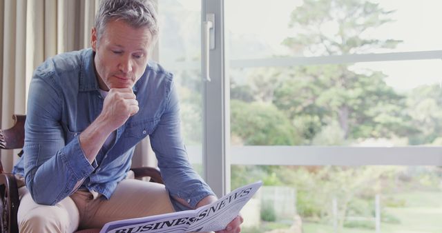 Middle-aged man reading business newspaper in modern living room - Download Free Stock Images Pikwizard.com