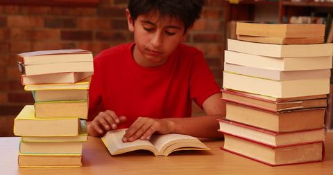 Young Boy Immersed in Reading Surrounded by Book Stacks - Download Free Stock Images Pikwizard.com