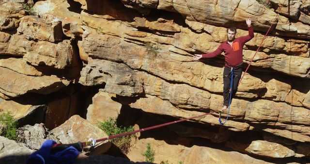 Person balancing on slackline suspended over rocky canyon. Useful for articles and advertisements on adventure activity, outdoor sports, extreme sports, balancing, thrill-seeking.