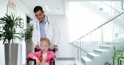 Doctor Assisting Child in Wheelchair in Hospital Corridor
