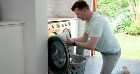 Senior man doing laundry at home in sunlit room